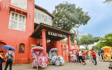 Stadthuys Malacca with colorful trishaws and tourists exploring the historic site.