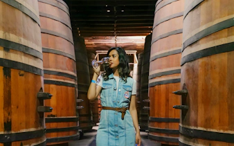 Tourist tasting wine at Cousiño Macul winery surrounded by large wooden barrels.