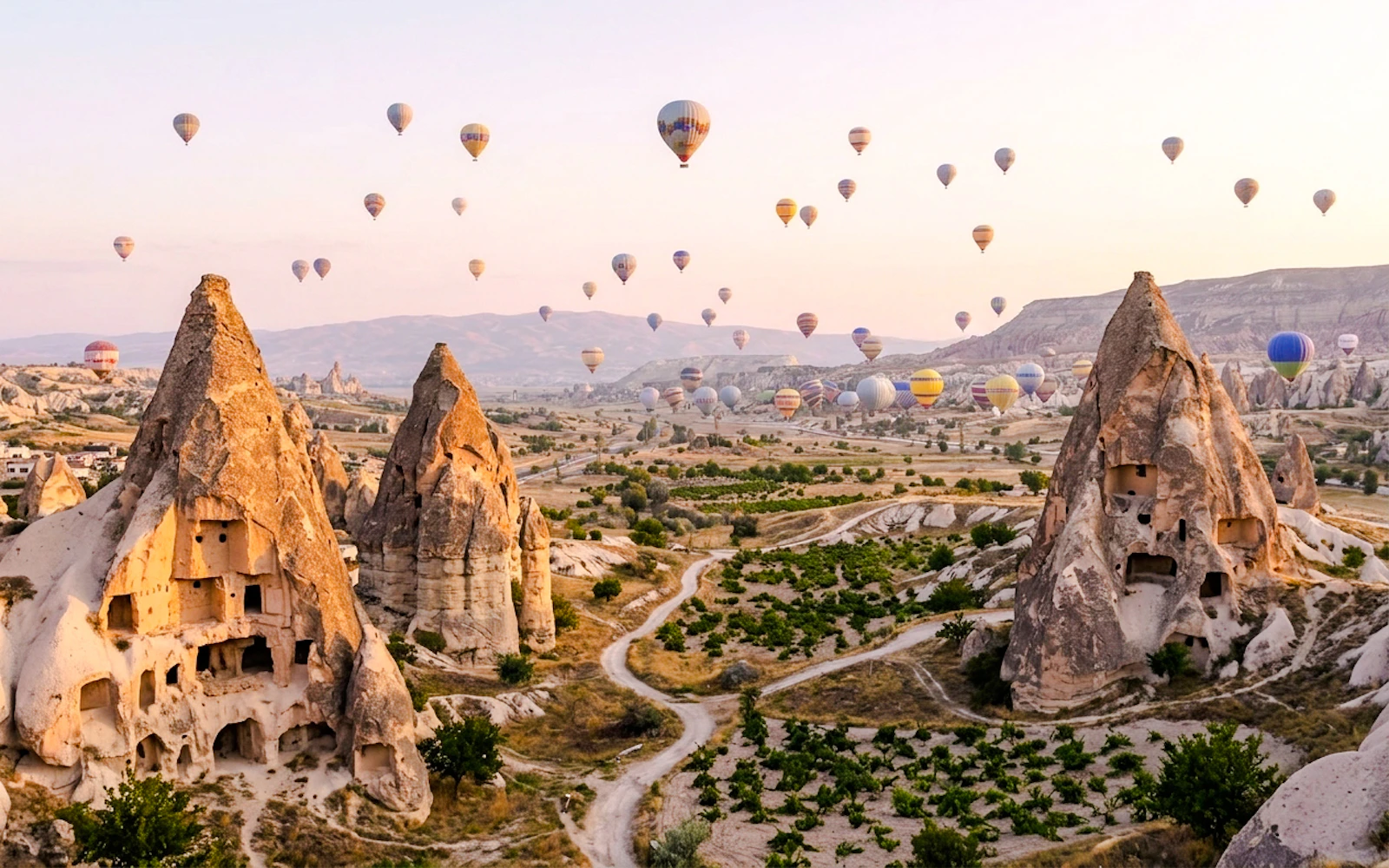 Hot air balloons over Cappadocia's rock formations during a private tour.