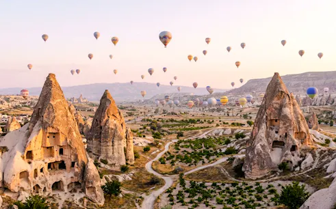 Hot air balloons over Cappadocia's rock formations during a private tour.