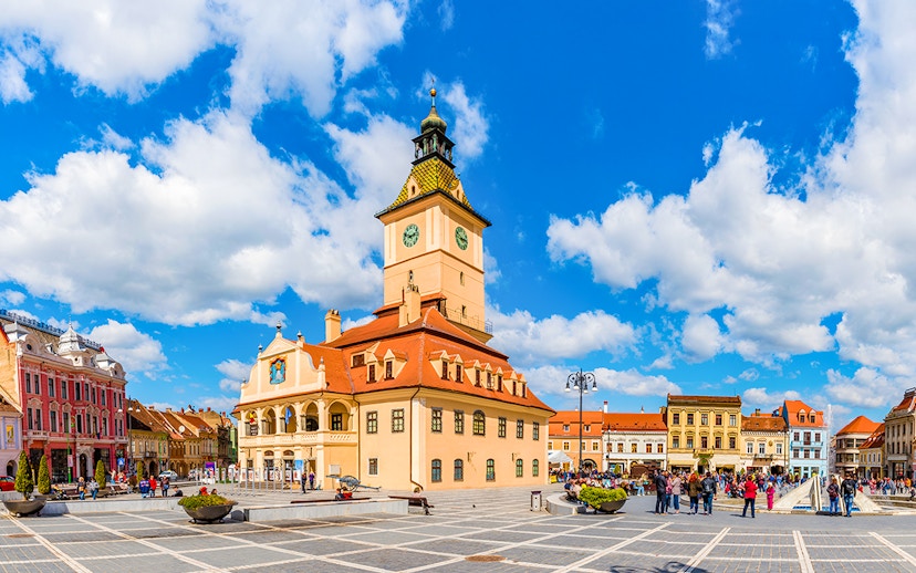 Council Square in Brasov with historic buildings and people walking.