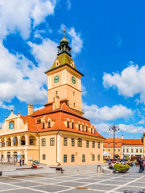 Council Square in Brasov with historic buildings and people walking.