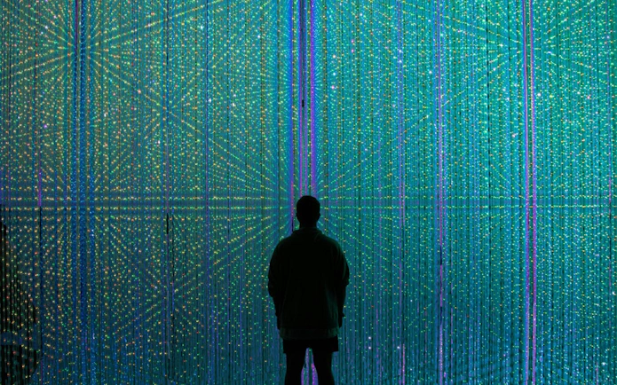 Visitor at teamLab Borderless Tokyo surrounded by colorful digital light display.