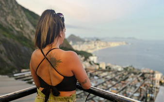 Person enjoying panoramic view of Rio de Janeiro from Vidigal, overlooking cityscape and coastline.