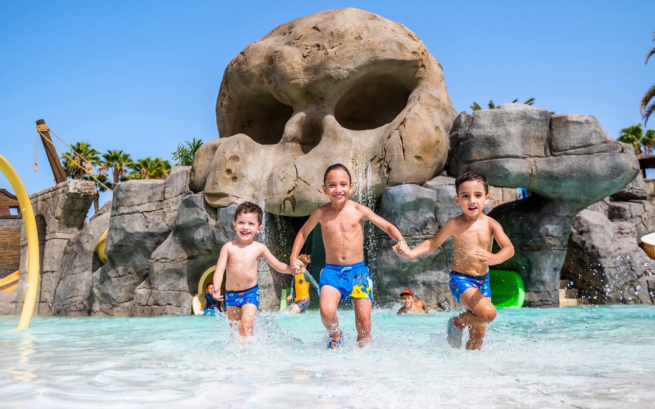 Kids playing in water near skull rock at Aqualand Maspalomas water park.