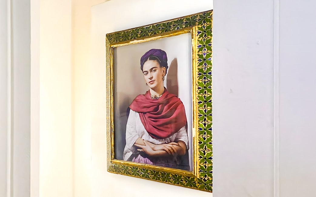 Frida Kahlo portrait in ornate frame at Frida Kahlo Museum, Mexico City.