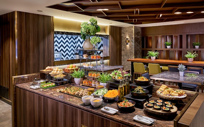Buffet spread at Plaza Premium Lounge, Penang International Airport, featuring salads, pastries, and beverages.