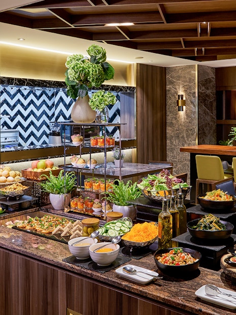 Buffet spread at Plaza Premium Lounge, Penang International Airport, featuring salads, pastries, and beverages.