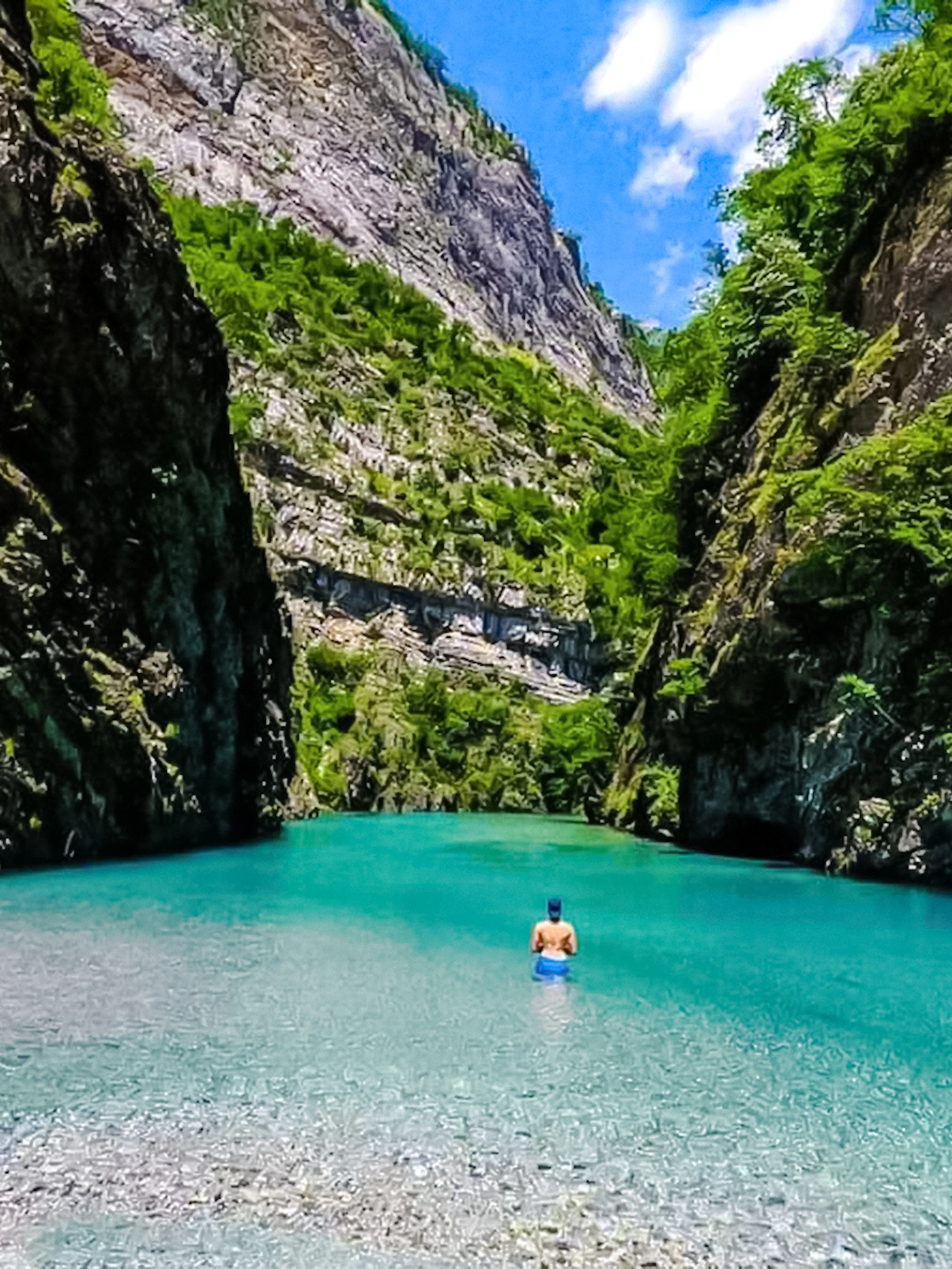 Guest swimming in clear waters of Komani Lake, surrounded by rocky cliffs, during Tirana day trip.