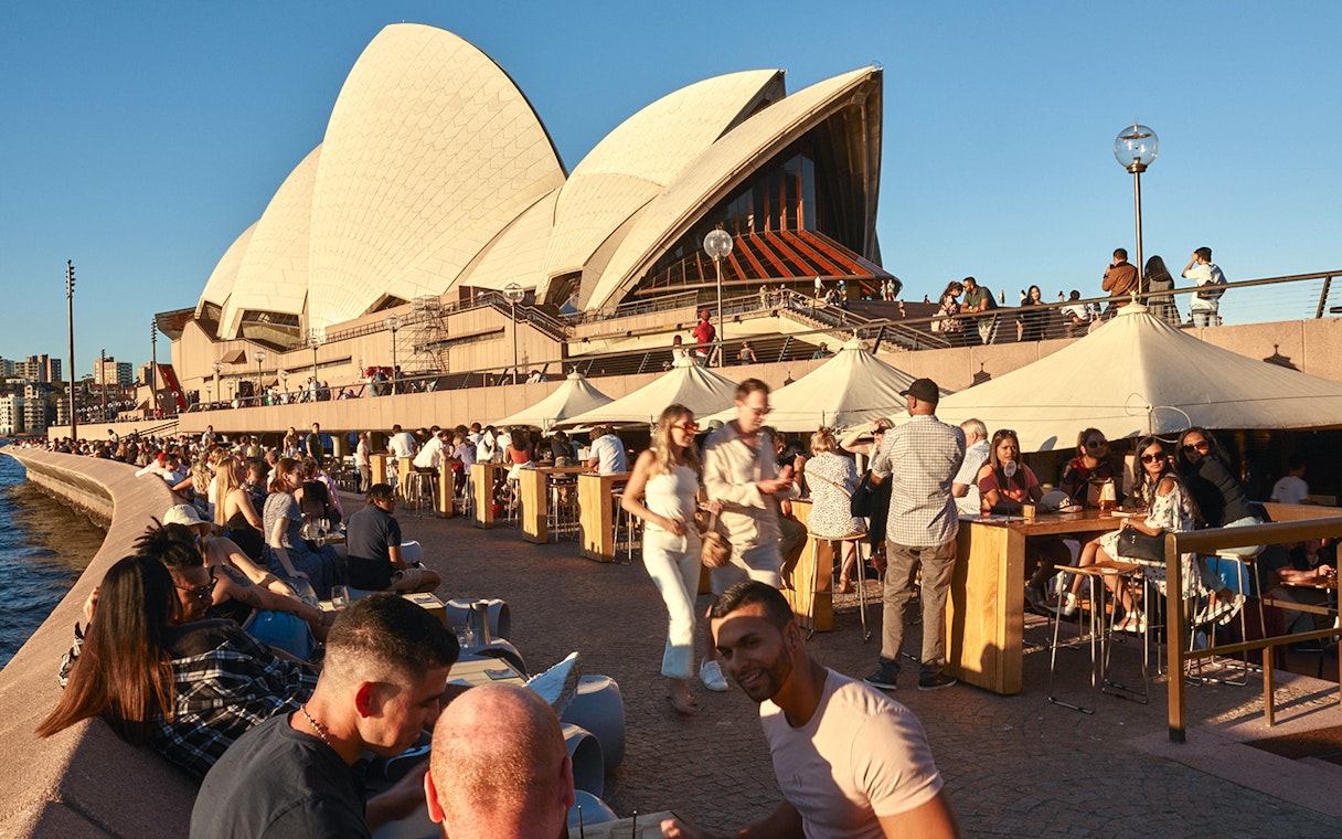 Sydney Opera House tour guests dining outdoors by the waterfront.