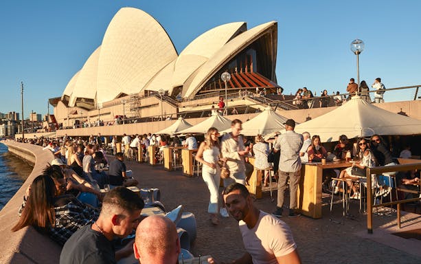 Sydney Opera House tour guests dining outdoors by the waterfront.