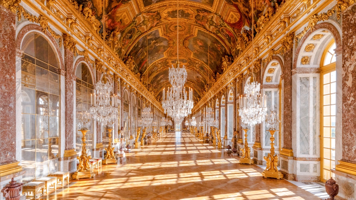 Gallery of Mirrors in Versailles Palace, Paris, showcasing ornate chandeliers and reflective mirrors.