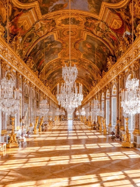 Gallery of Mirrors in Versailles Palace, Paris, showcasing ornate chandeliers and reflective mirrors.