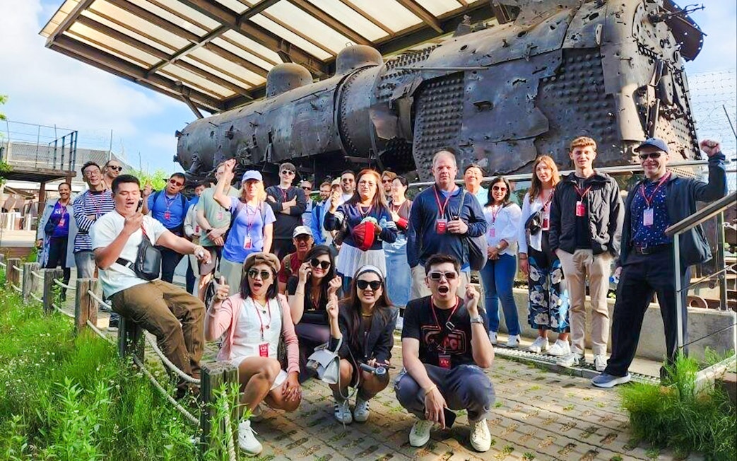Tour group at bullet-riddled steam locomotive, Korean War relic, DMZ, South Korea.