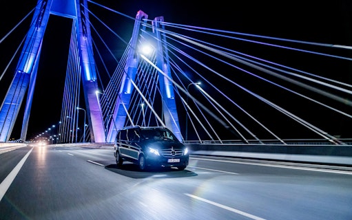 Private transfer car crossing illuminated bridge at night in Krakow.