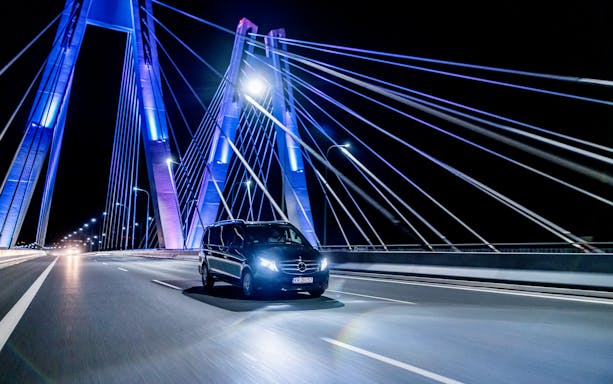 Private transfer car crossing illuminated bridge at night in Krakow.