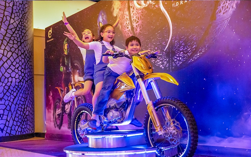 Children posing on a display motorcycle at La Perle by Dragone in Dubai.