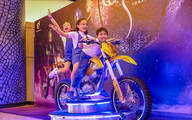 Children posing on a display motorcycle at La Perle by Dragone in Dubai.