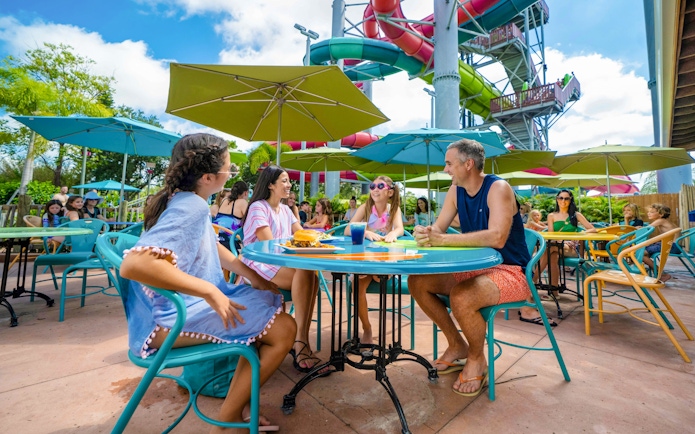 Group dining at Aquatica Orlando with water slides in the background.