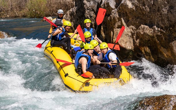 Group rafting on the Cetina River, navigating rapids in a yellow inflatable raft.