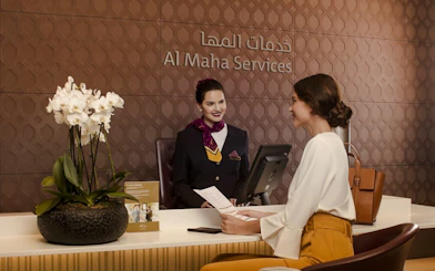 Al Maha Lounge reception at Doha Hamad International Airport with staff assisting a traveler.