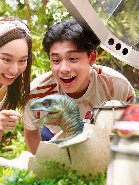 Visitors interacting with a dinosaur exhibit at Universal Studios Singapore.