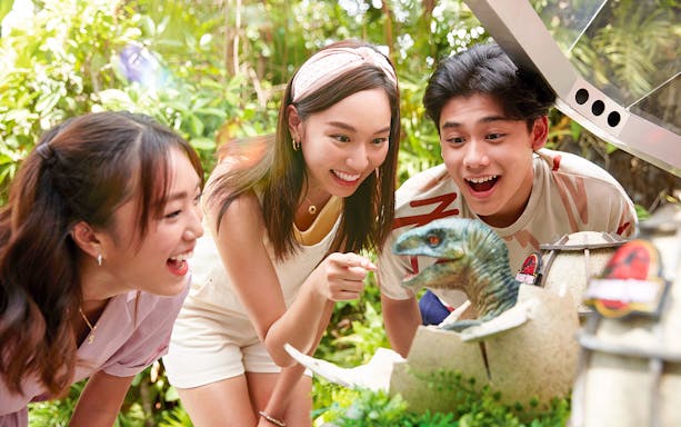 Visitors interacting with a dinosaur exhibit at Universal Studios Singapore.