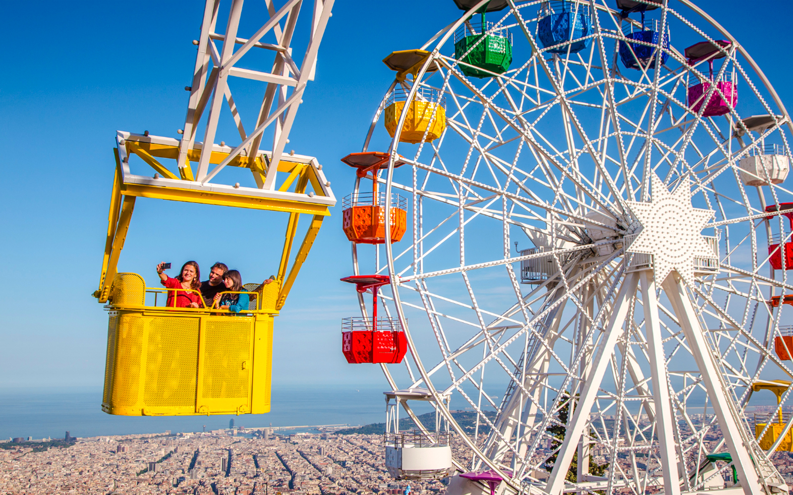Talaia ride at Tibidabo Amusement Park with Ferris wheel and city view.