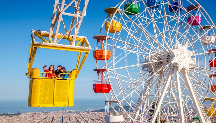 Talaia ride at Tibidabo Amusement Park with Ferris wheel and city view.
