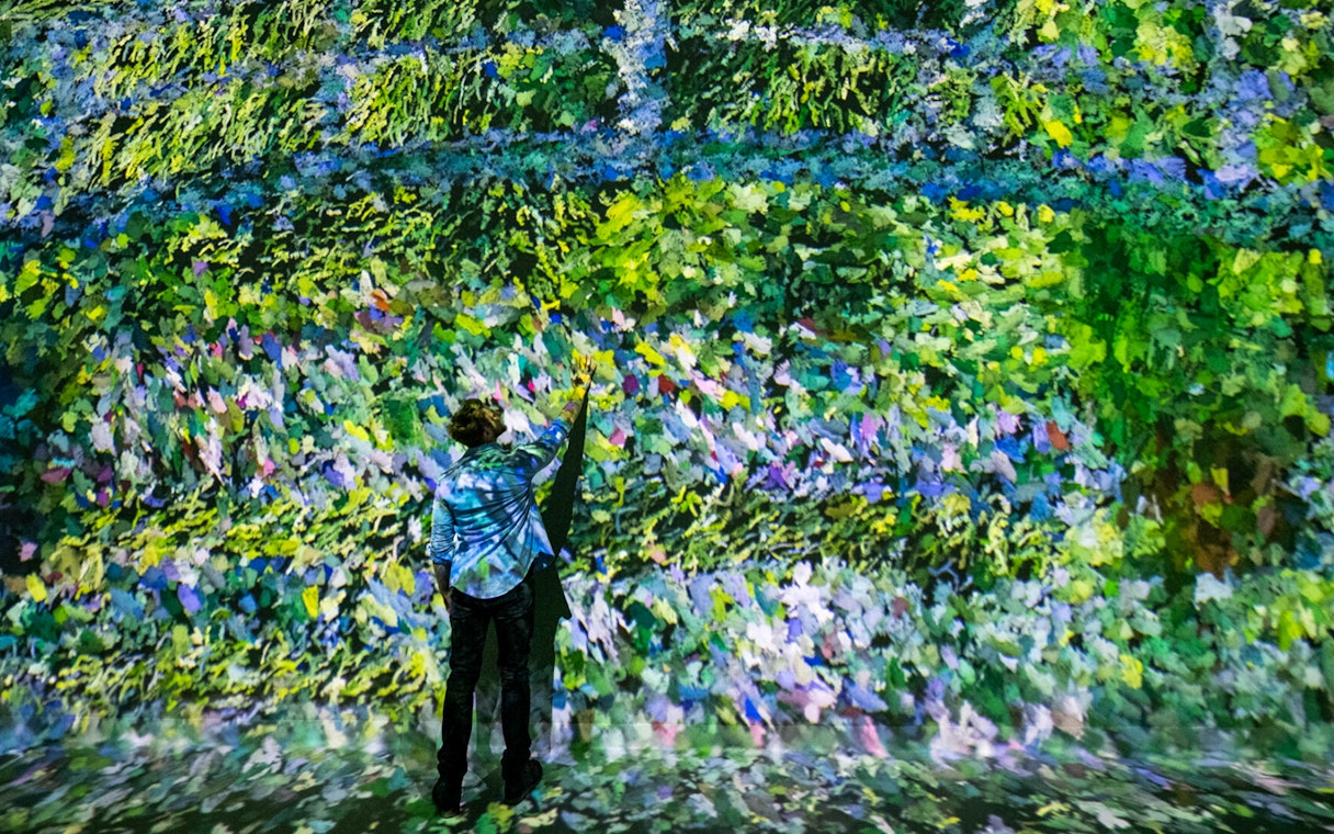 Visitor interacting with vibrant digital art at Colour in Motion Gallery, Frameless London.