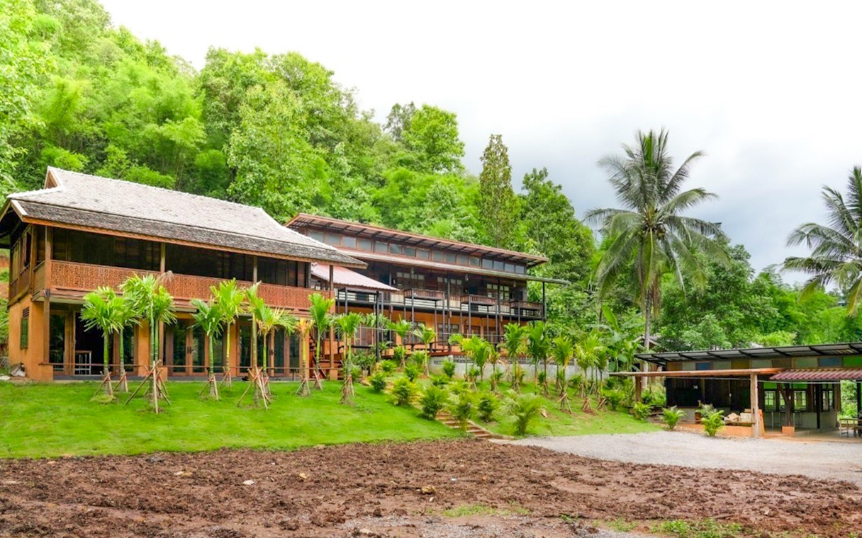 Homestay buildings surrounded by lush greenery at Elephant Jungle Sanctuary, Chiang Mai.