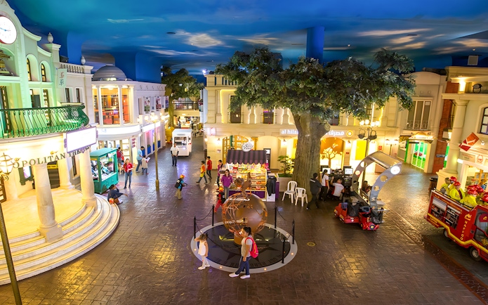 KidZania Abu Dhabi streets with children exploring interactive shops and activities.