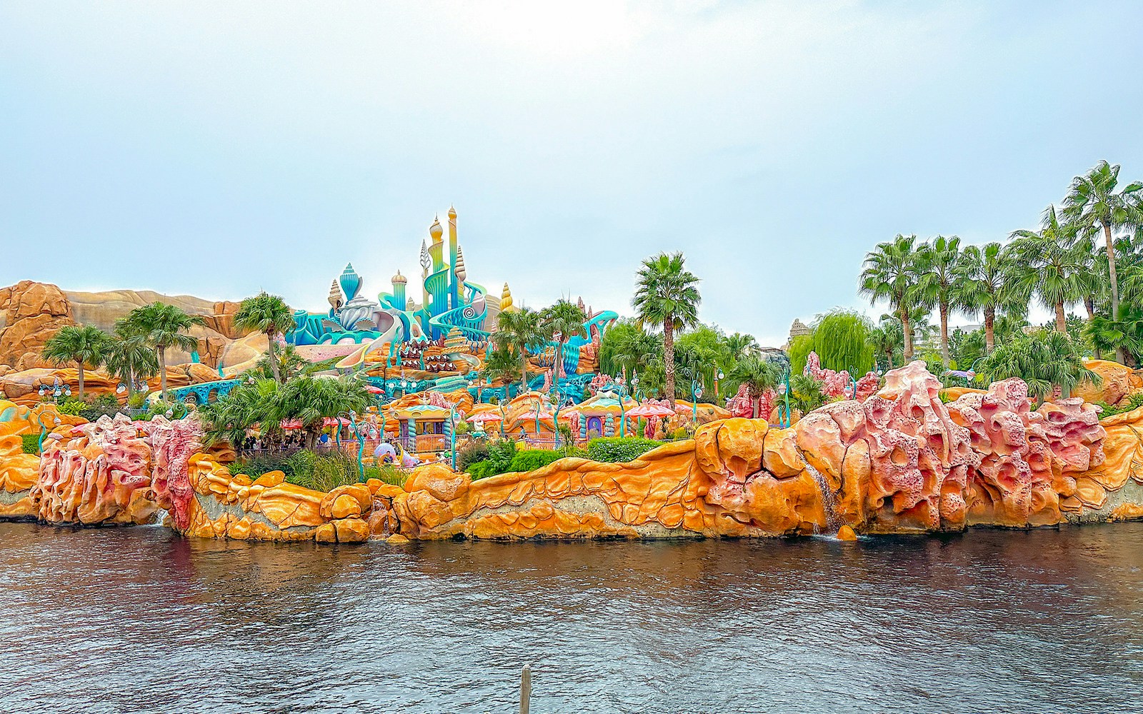 Colorful Mermaid Lagoon at Tokyo Disneyland with vibrant coral structures and palm trees.