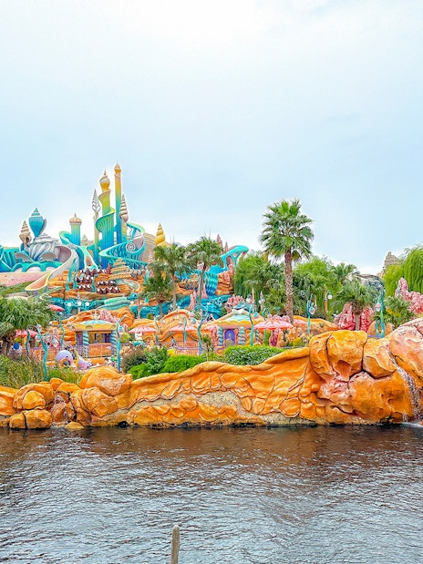 Colorful Mermaid Lagoon at Tokyo Disneyland with vibrant coral structures and palm trees.