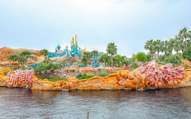 Colorful Mermaid Lagoon at Tokyo Disneyland with vibrant coral structures and palm trees.