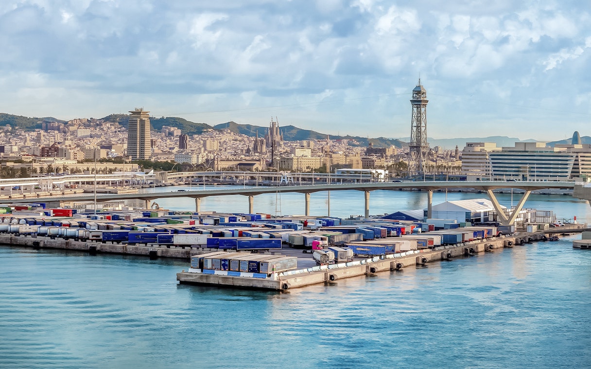 Port of Barcelona with city skyline, featuring Magic Sailing Experience with local captain.
