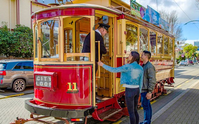 Couple boarding vintage tram in Christchurch city loop.