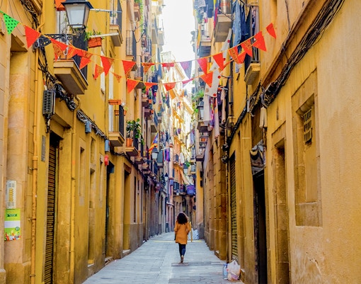 El Born street in Barcelona with colorful flags and historic buildings.