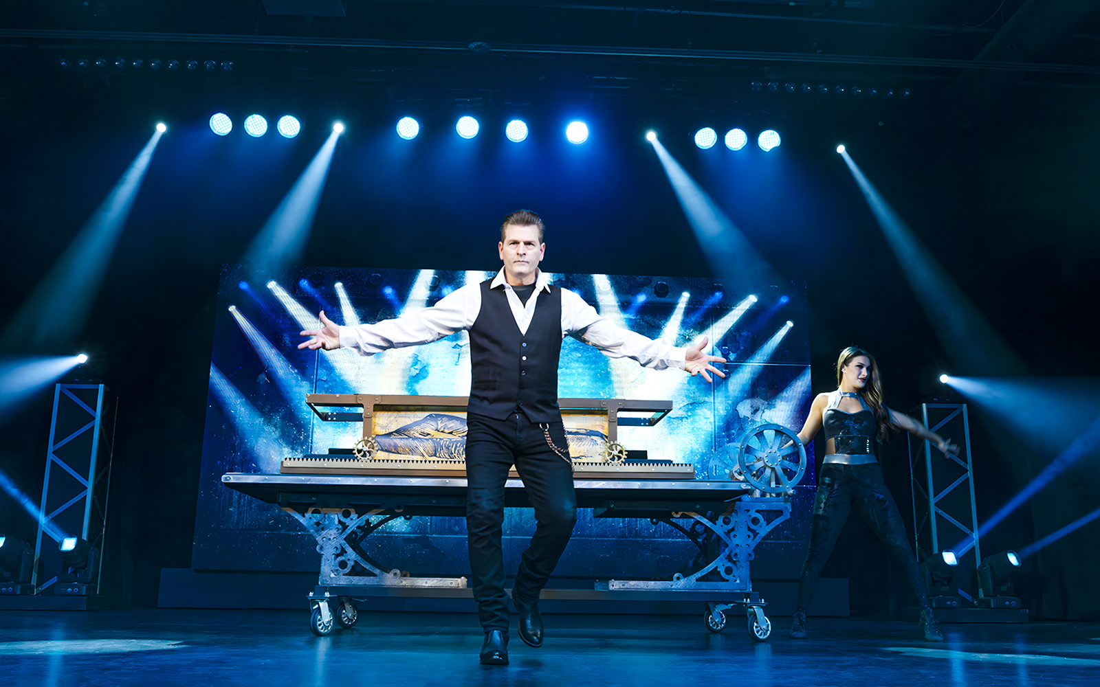 Magician performing on stage with assistant during Evolution Magic Show.