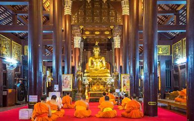 Monks meditating in front of a golden Buddha statue in a Chiang Mai temple.