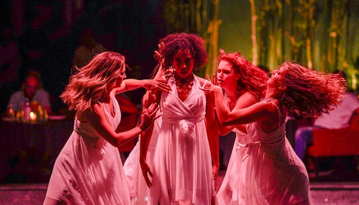 Performers in white dresses dancing at Nouba Restaurant Dinner Show.