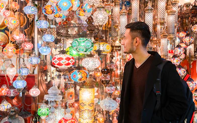 Man admiring colorful lanterns at Istanbul's Grand Bazaar.