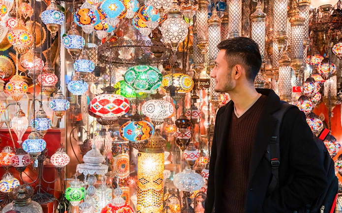 Man admiring colorful lanterns at Istanbul's Grand Bazaar.