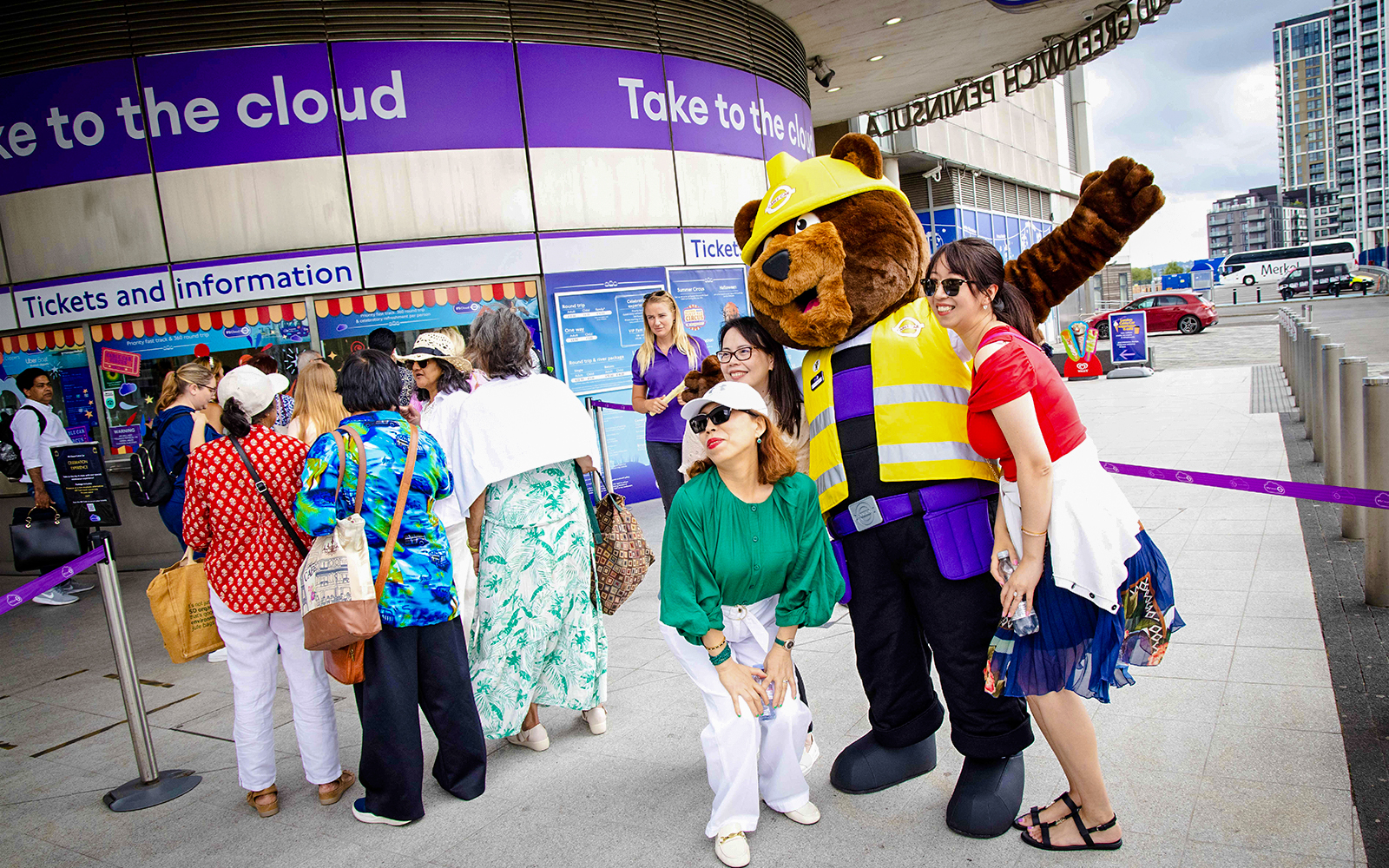 Guests posing with a mascot at IFS Cloud Cable Car entrance in London.