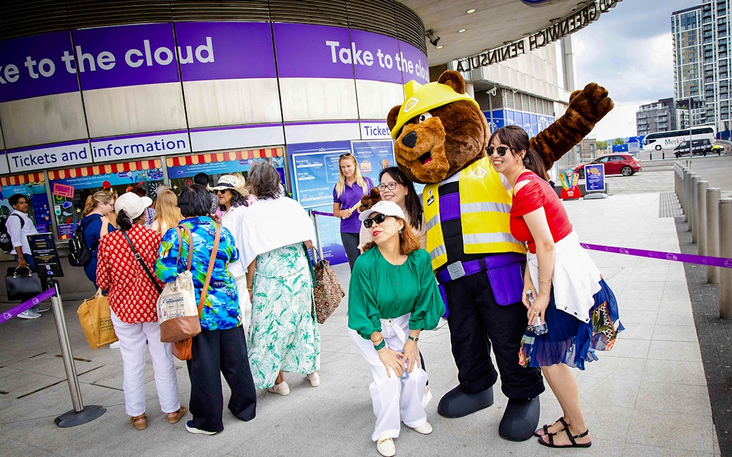 Guests posing with a mascot at IFS Cloud Cable Car entrance in London.
