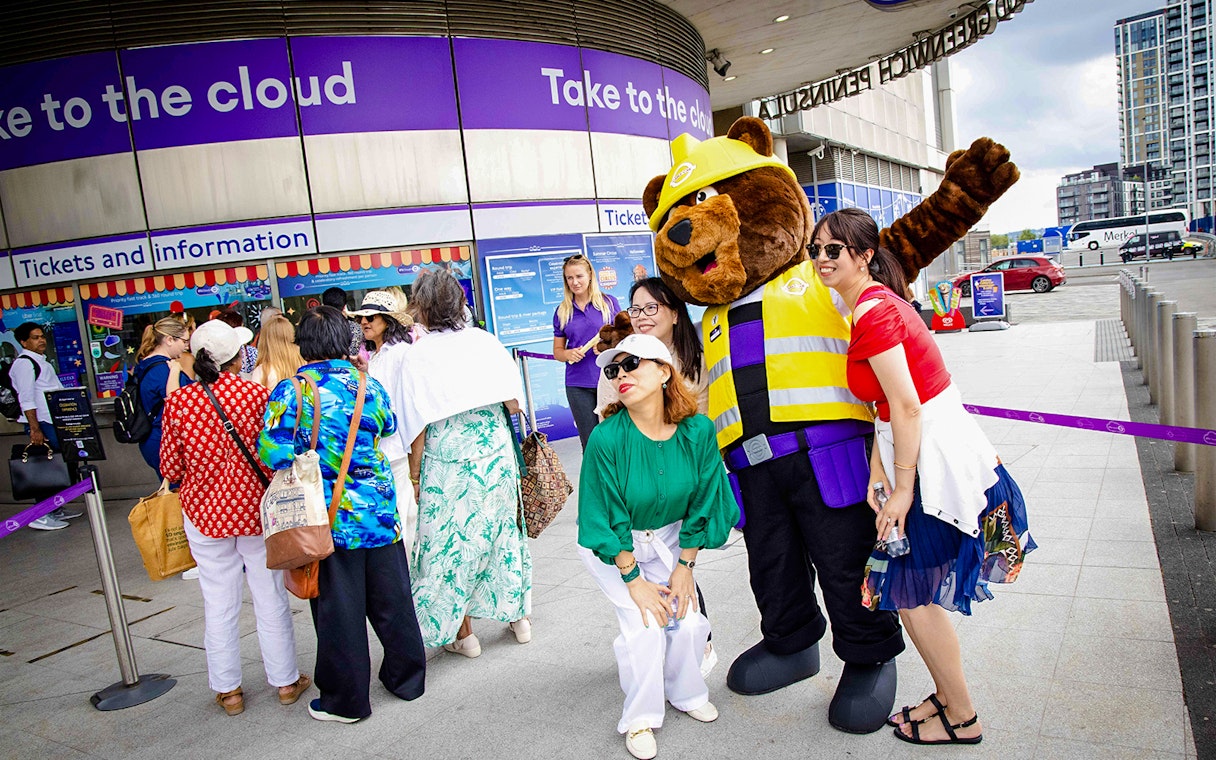 Guests posing with a mascot at IFS Cloud Cable Car entrance in London.