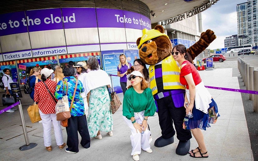 Guests posing with a mascot at IFS Cloud Cable Car entrance in London.