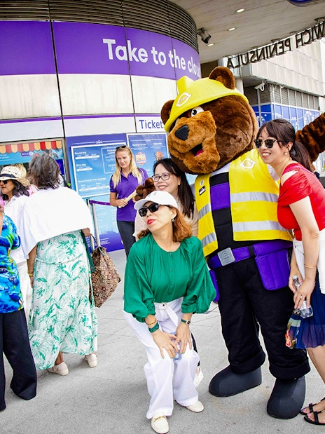 Guests posing with a mascot at IFS Cloud Cable Car entrance in London.