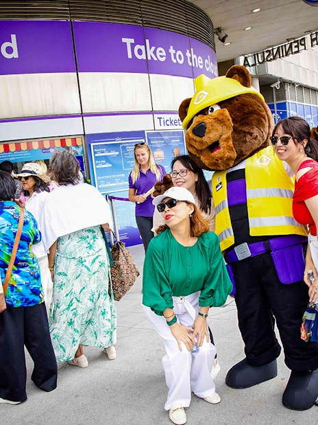 Guests posing with a mascot at IFS Cloud Cable Car entrance in London.
