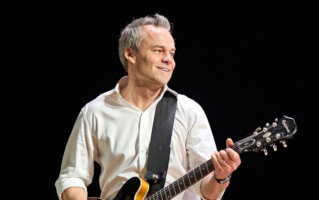 Musician playing guitar on stage during Inter Alia performance.